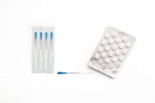 aghi per agopuntura e blister di compresse su sfondo bianco