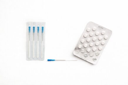 aghi per agopuntura e blister di compresse su sfondo bianco